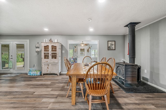 dining space with ceiling fan, a wood stove, a textured ceiling, recessed lighting, and wood finished floors