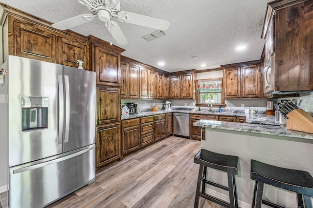 kitchen with a sink, stainless steel appliances, a textured ceiling, and visible vents