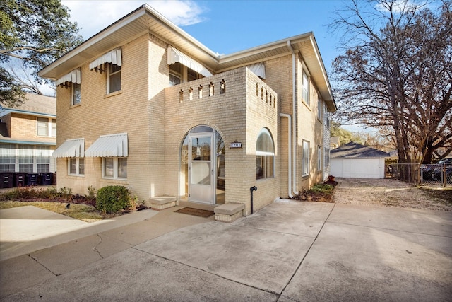 view of front of home featuring fence, a balcony, and brick siding