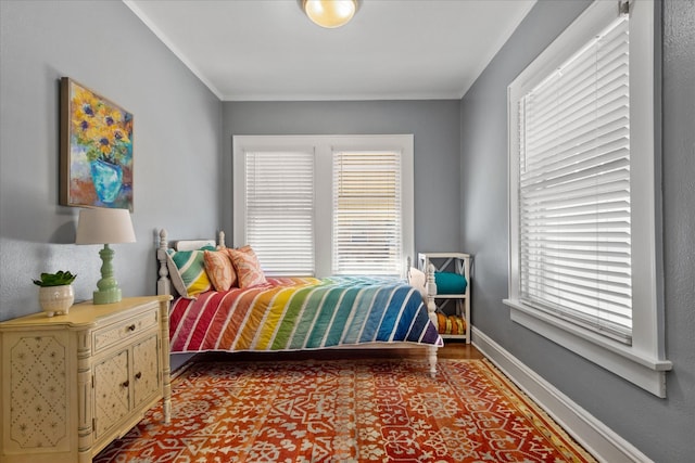 bedroom featuring wood finished floors, crown molding, and baseboards