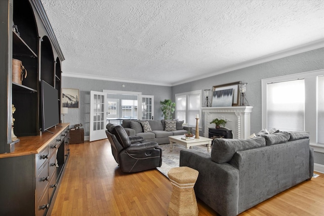 living room with a textured ceiling, light wood-style flooring, a textured wall, ornamental molding, and a fireplace
