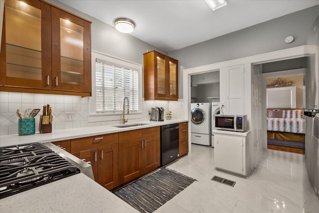 kitchen featuring separate washer and dryer, stainless steel microwave, dishwasher, a sink, and visible vents
