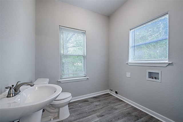 bathroom featuring baseboards, wood finished floors, toilet, and a sink