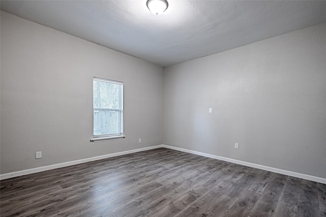 empty room featuring baseboards and dark wood finished floors