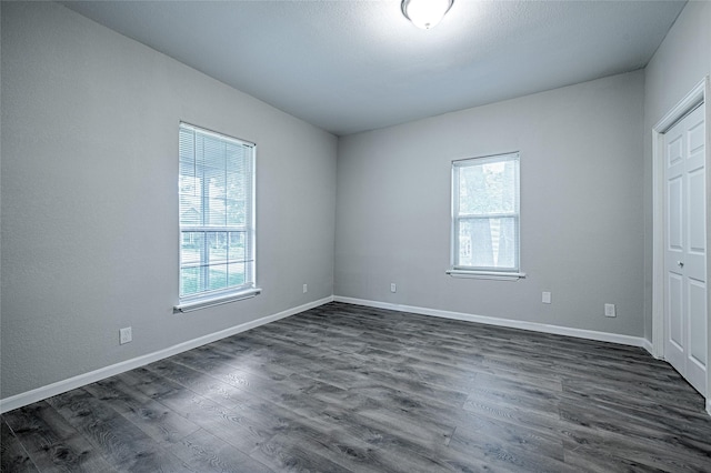 unfurnished bedroom with a closet, baseboards, and dark wood finished floors