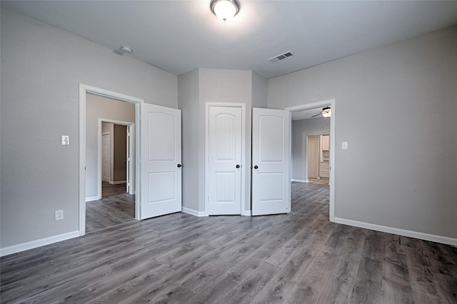 unfurnished bedroom with baseboards, visible vents, wood finished floors, and a closet