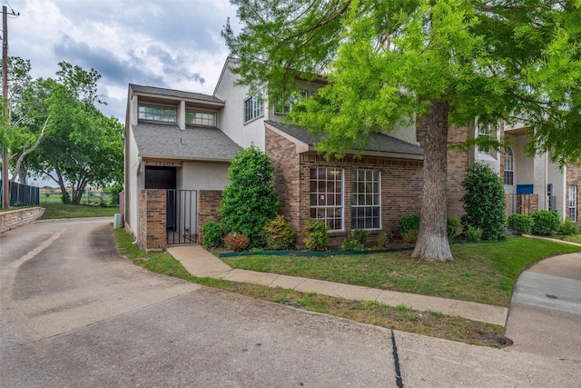 view of property featuring fence, stucco siding, roof with shingles, and brick siding