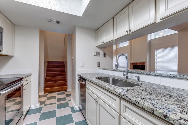 kitchen featuring a sink, stainless steel appliances, white cabinetry, and visible vents