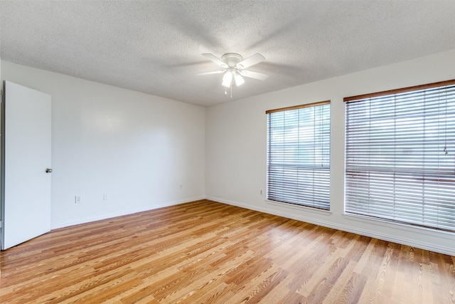 unfurnished room featuring a ceiling fan, baseboards, a textured ceiling, and light wood-type flooring