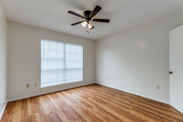 unfurnished room with baseboards, a ceiling fan, light wood-type flooring, and a textured ceiling