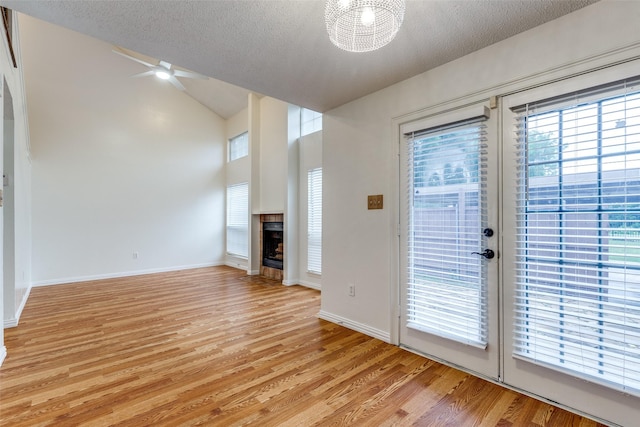 unfurnished living room with baseboards, a textured ceiling, light wood-style flooring, and a fireplace