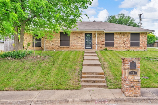 single story home featuring fence, a shingled roof, brick siding, and a front yard