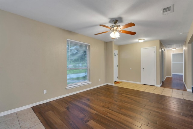unfurnished room with ceiling fan, attic access, baseboards, wood finished floors, and visible vents