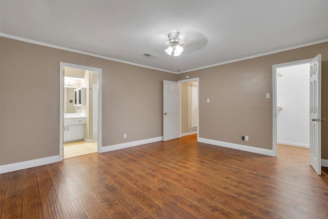 unfurnished bedroom featuring visible vents, baseboards, crown molding, and hardwood / wood-style flooring