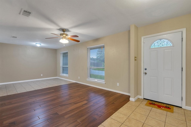 foyer entrance with a wealth of natural light, ceiling fan, light wood-type flooring, and visible vents