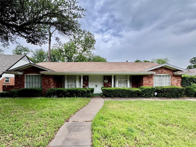 single story home featuring a shingled roof, brick siding, and a front lawn