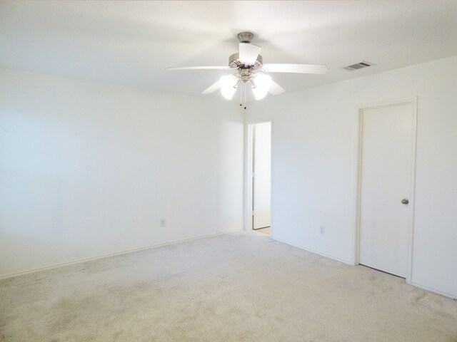 empty room with light colored carpet, visible vents, and a ceiling fan
