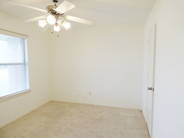 spare room with baseboards, a ceiling fan, a healthy amount of sunlight, and light colored carpet