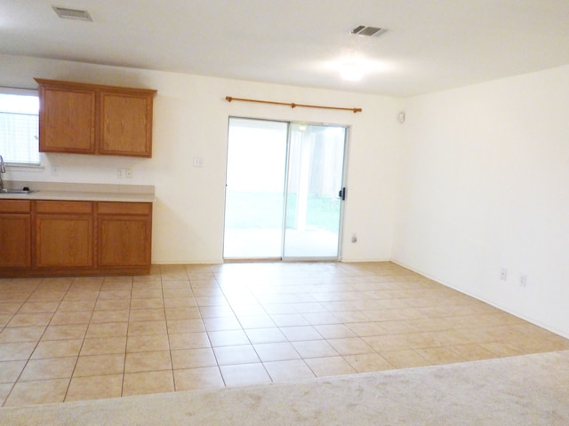 kitchen featuring a sink, light tile patterned flooring, visible vents, and brown cabinets