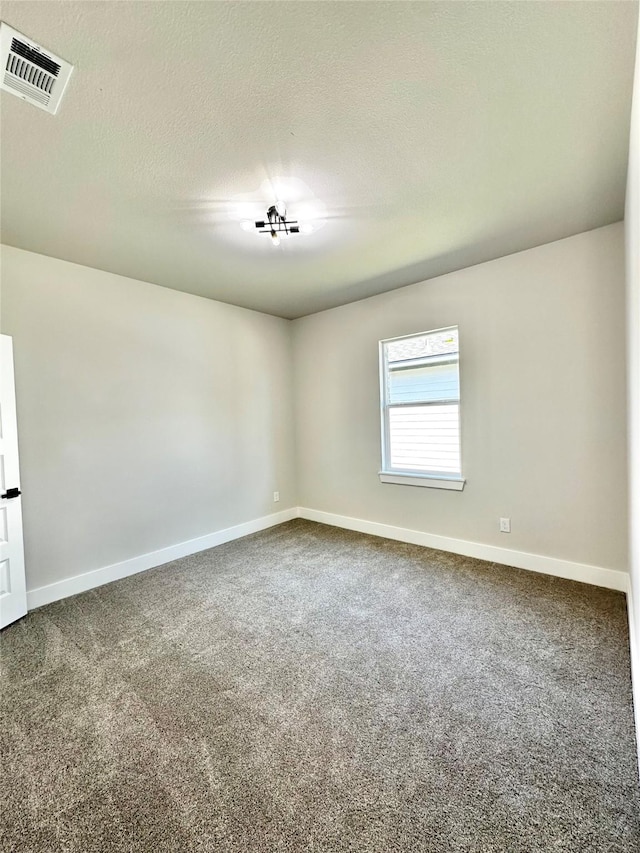 empty room with baseboards, visible vents, a textured ceiling, and carpet flooring