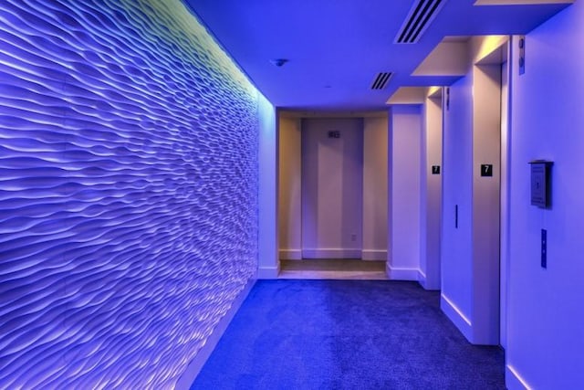 hall featuring dark colored carpet and baseboards