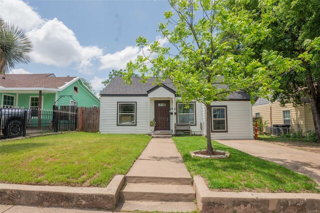view of front of house with fence, roof with shingles, and a front yard