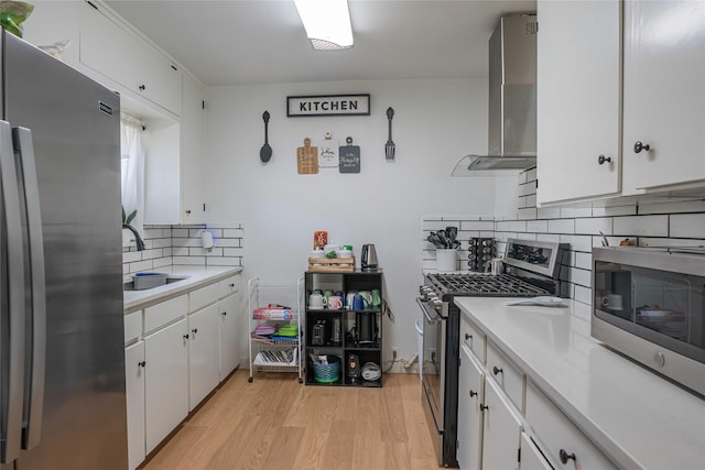 kitchen with decorative backsplash, a sink, appliances with stainless steel finishes, light countertops, and wall chimney exhaust hood