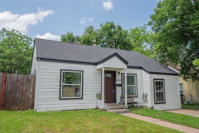bungalow featuring a front yard, roof with shingles, and fence