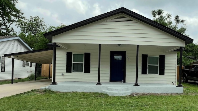 bungalow-style house with covered porch, a carport, a front lawn, and driveway