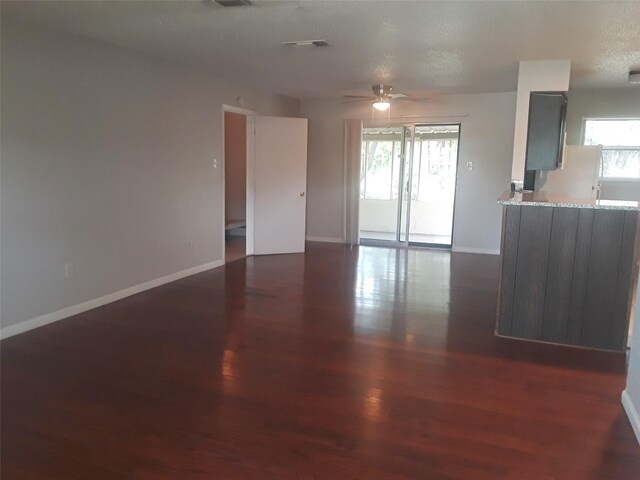 unfurnished living room featuring dark wood-style floors, visible vents, baseboards, and plenty of natural light