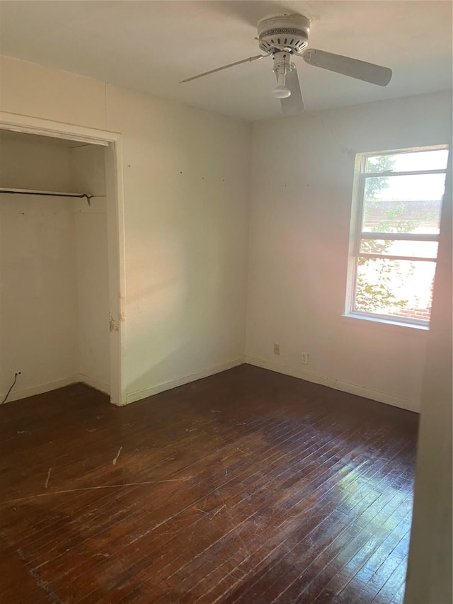 unfurnished bedroom with baseboards, a ceiling fan, dark wood-style flooring, and a closet