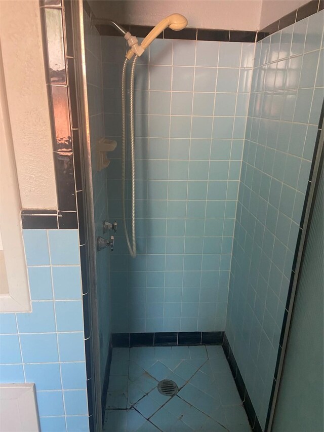 bathroom featuring tile walls, a tile shower, and tile patterned flooring