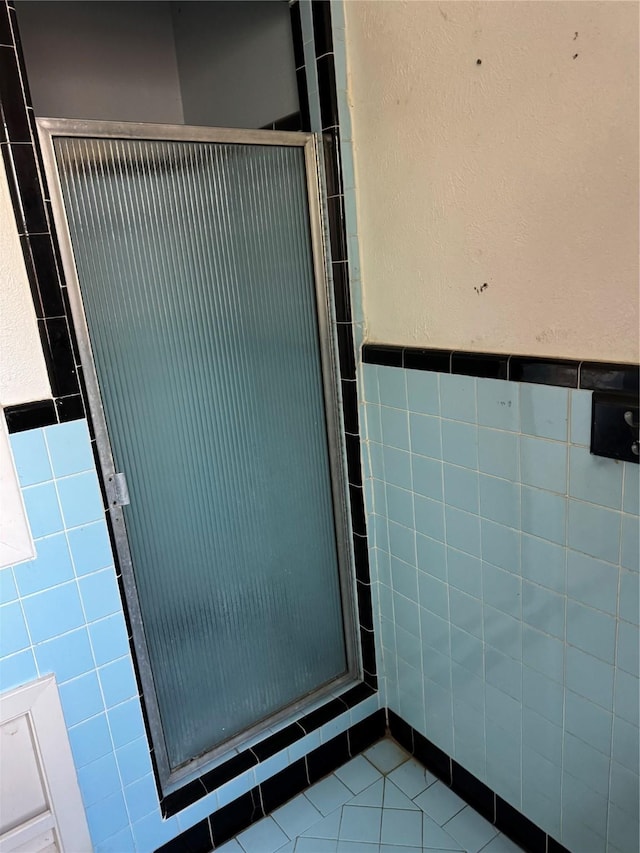 bathroom featuring tile patterned floors, a stall shower, and tile walls