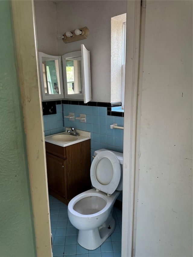 half bathroom featuring tile walls, toilet, tile patterned flooring, and vanity