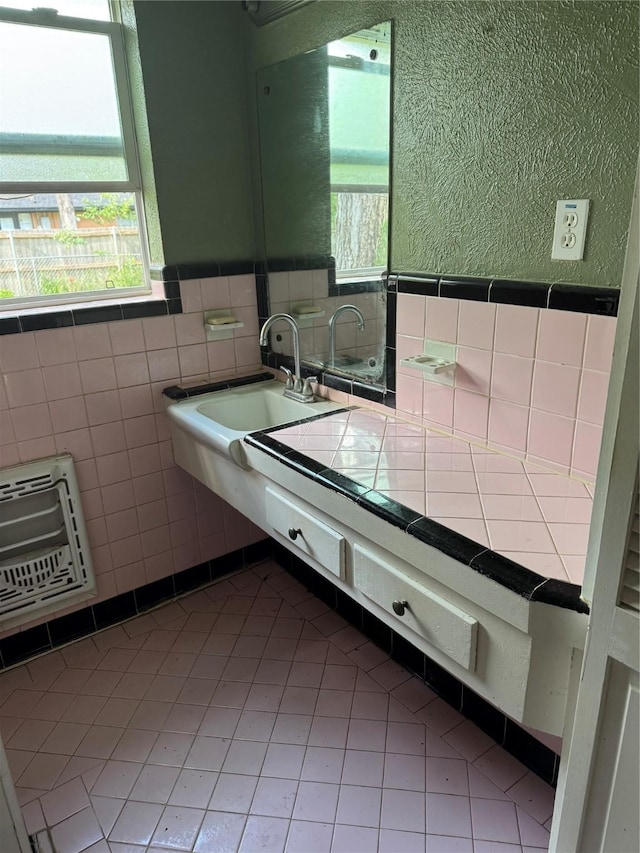 bathroom featuring tile walls, a sink, heating unit, tile patterned floors, and wainscoting