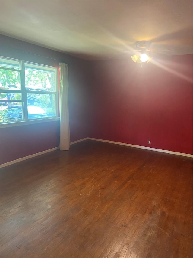unfurnished room with baseboards and dark wood finished floors