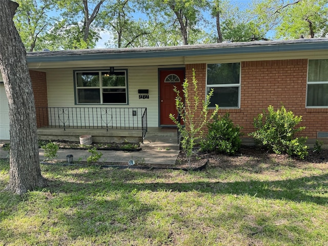 view of front facade featuring a front lawn, an attached garage, covered porch, and brick siding