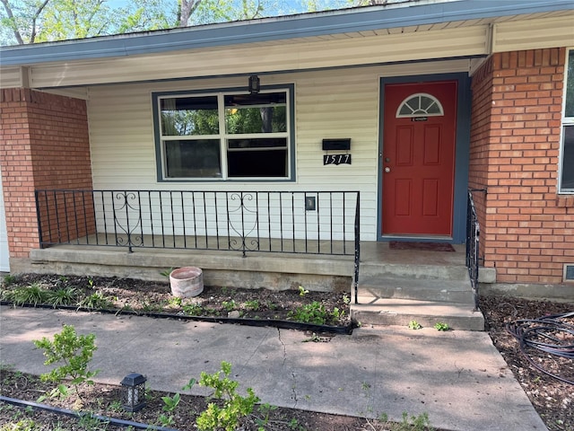 property entrance with covered porch and brick siding