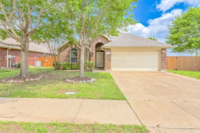 view of front of home with roof with shingles, fence, brick siding, a front lawn, and a garage