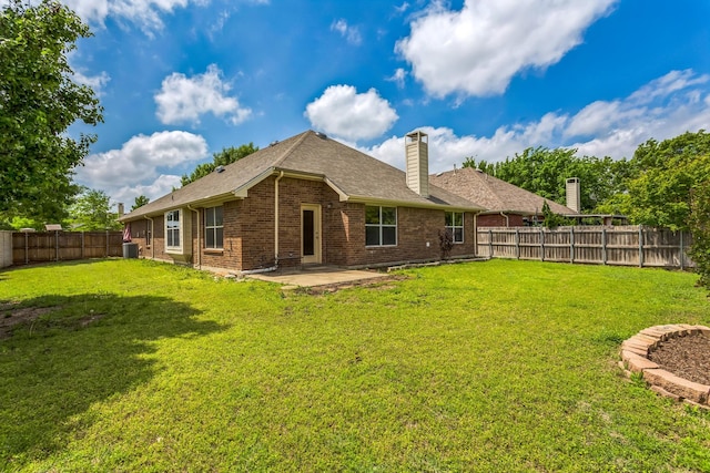 back of property with a patio, brick siding, a fenced backyard, a lawn, and a chimney