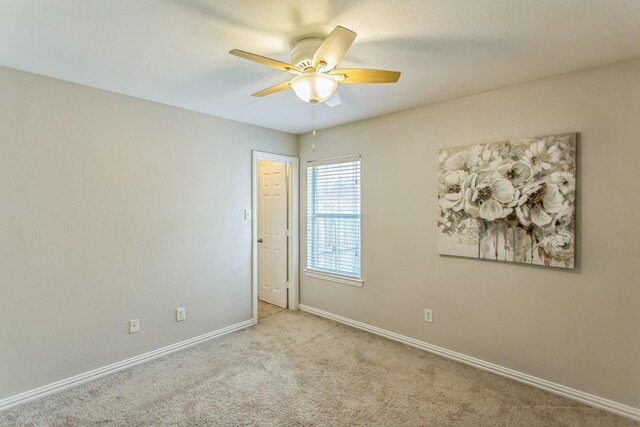 carpeted empty room featuring a ceiling fan and baseboards