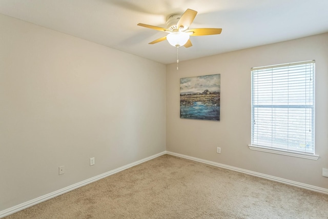 spare room featuring plenty of natural light, a ceiling fan, light carpet, and baseboards