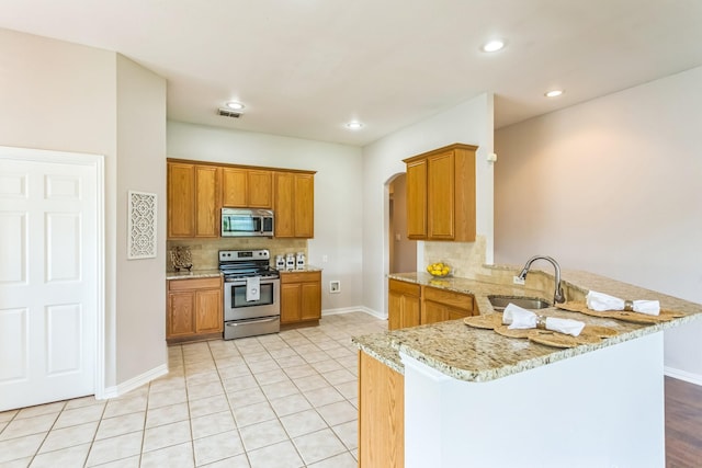 kitchen with a sink, appliances with stainless steel finishes, visible vents, a peninsula, and backsplash