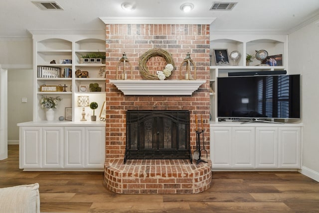 unfurnished living room featuring ornamental molding, visible vents, wood finished floors, and a fireplace