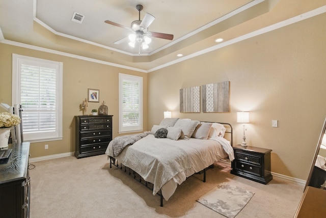 bedroom with crown molding, light colored carpet, and a raised ceiling