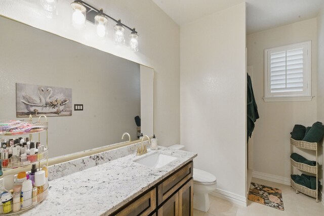 bathroom with toilet, tile patterned floors, vanity, and baseboards