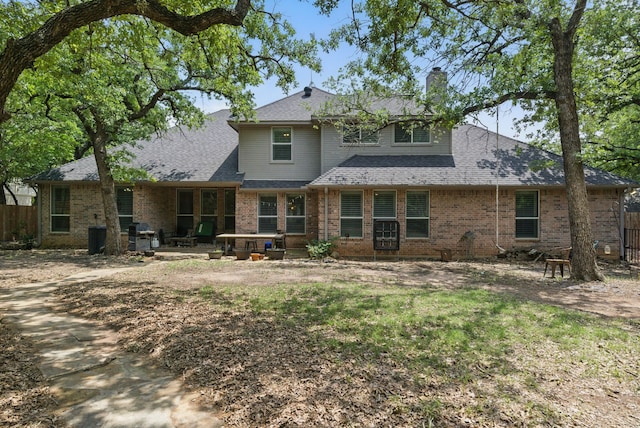 rear view of property with a chimney, brick siding, fence, and a patio area