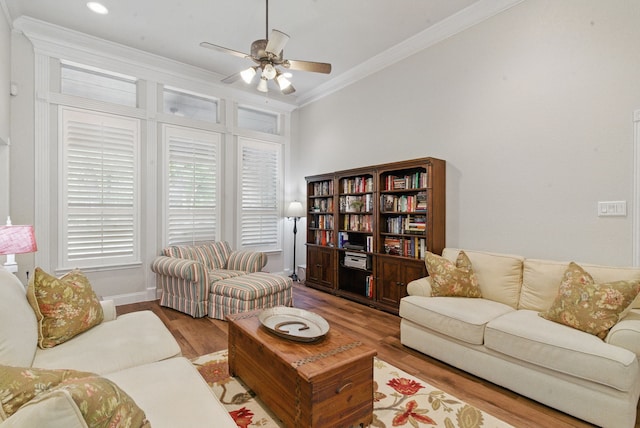 living room featuring baseboards, ornamental molding, a ceiling fan, and wood finished floors