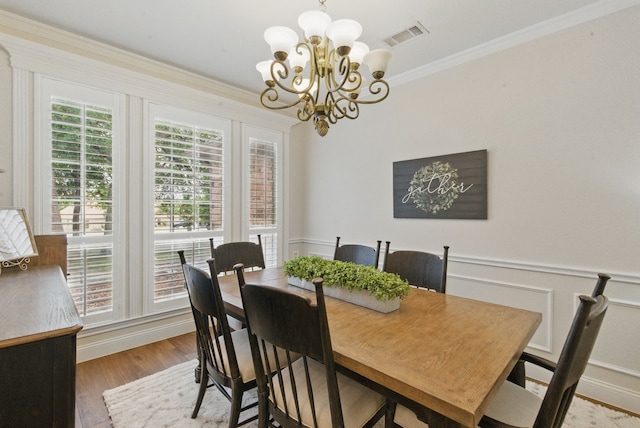 dining space with visible vents, ornamental molding, an inviting chandelier, and wood finished floors