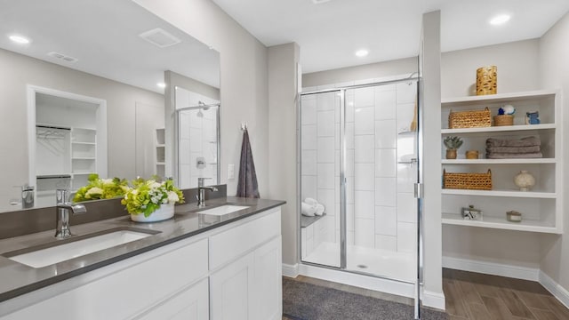 bathroom featuring a stall shower, a sink, wood finished floors, and visible vents
